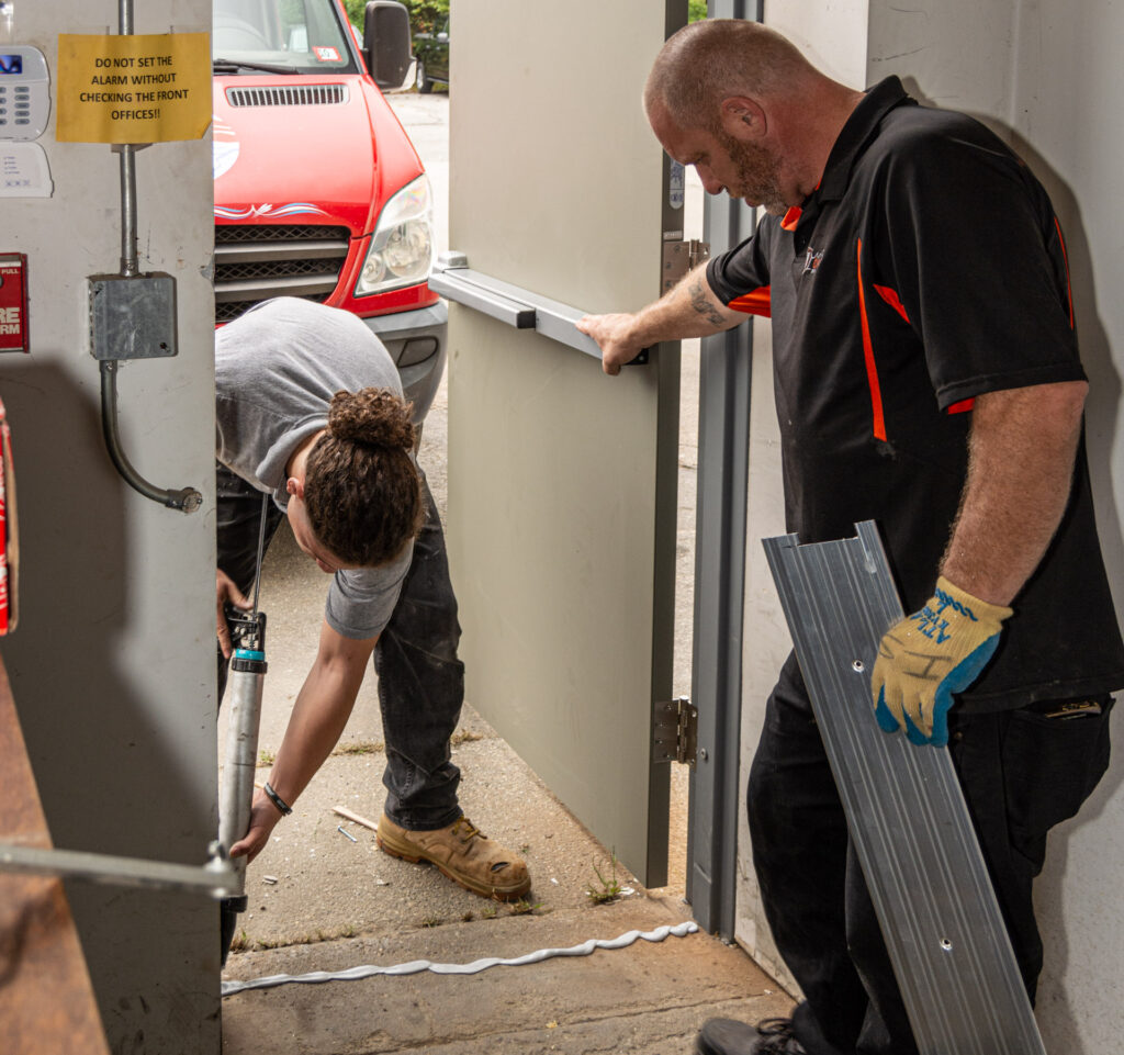 Two construction workers installing a commercial door threshold